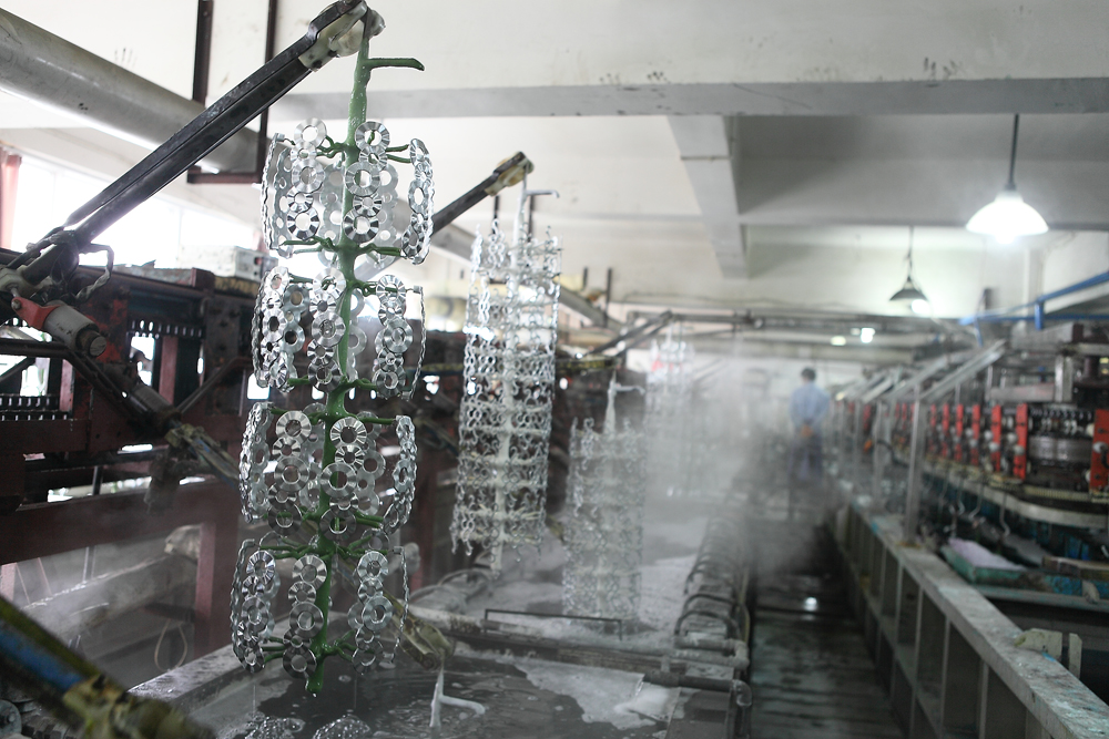 Metal hardware components suspended along a surface-finishing line