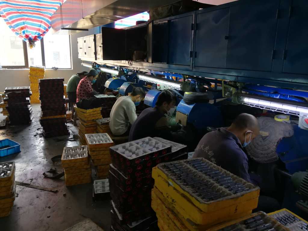 Workers at metal hardware polishing workstations